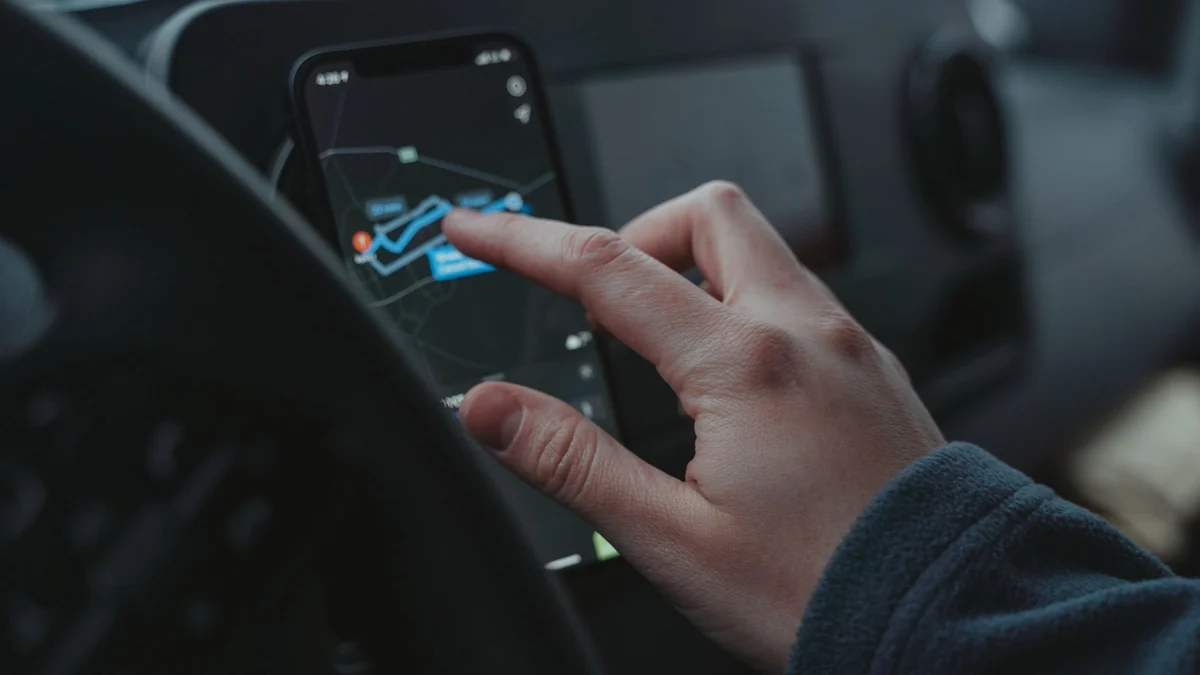 A finger touching a route map on a phone in a dashboard mount. Photo: Tima Miroshnichenko, Pexels